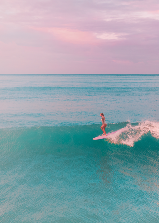Surfer Rides Turquoise Wave Under Pink Sky