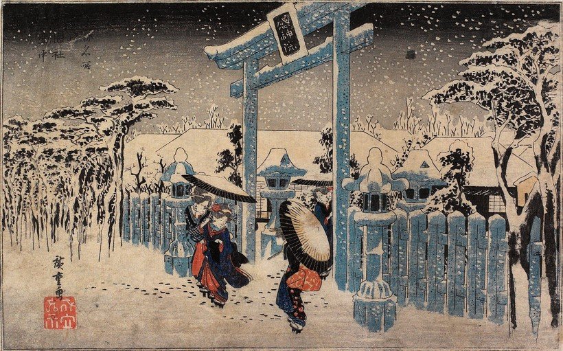 Japanese women walking in snow under a torii gate